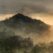 Watercolor-style landscape of misty rolling hills at sunrise with trees in the foreground